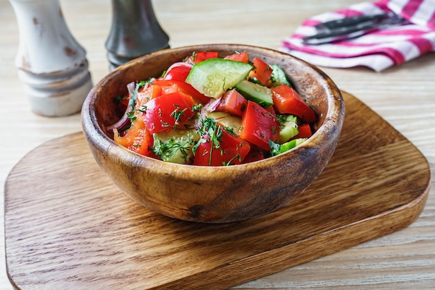 Salada de legumes de tomate e pepino em uma saladeira de madeira