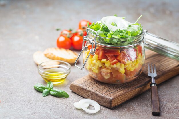 Salada de legumes em frasco de pedreiro caseiro saudável com tomate, milho, pimenta, rúcula e cebola