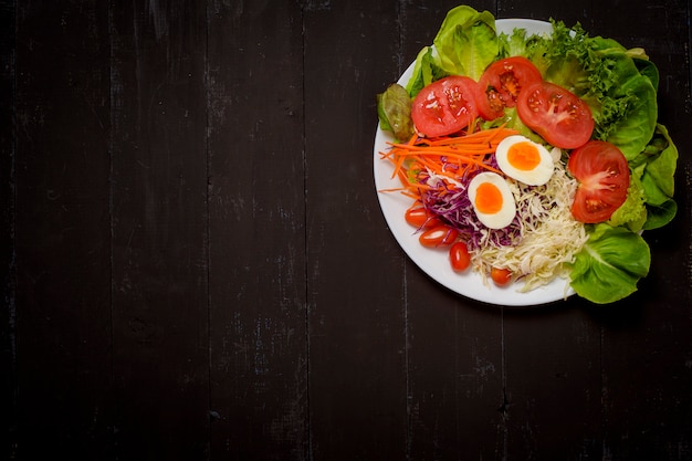 Salada de legumes em fundo preto de madeira