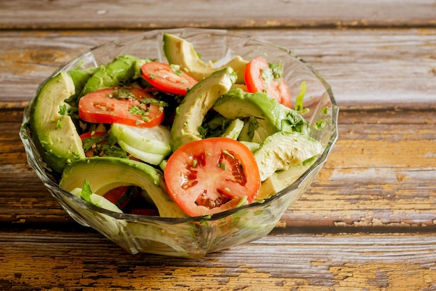 Salada de legumes em uma tigela de vidro sobre uma mesa de madeira. Legumes, comida saudável.