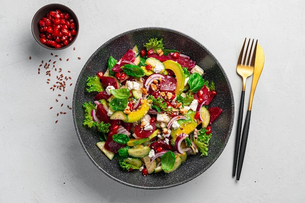 Salada de legumes fresca com abacate de beterraba e queijo feta em um fundo cinza Salada de legumes com romã e sementes de linho e gergelim Comida saudável