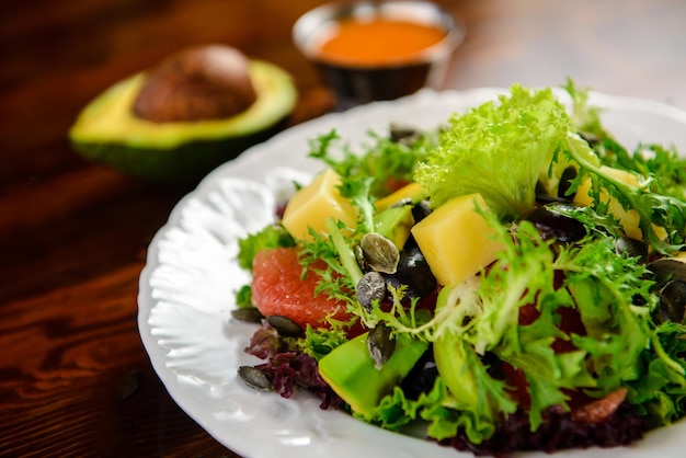 Foto salada de legumes fresca com sementes de abacate, toranja e abóbora em uma mesa de madeira em um restaurante