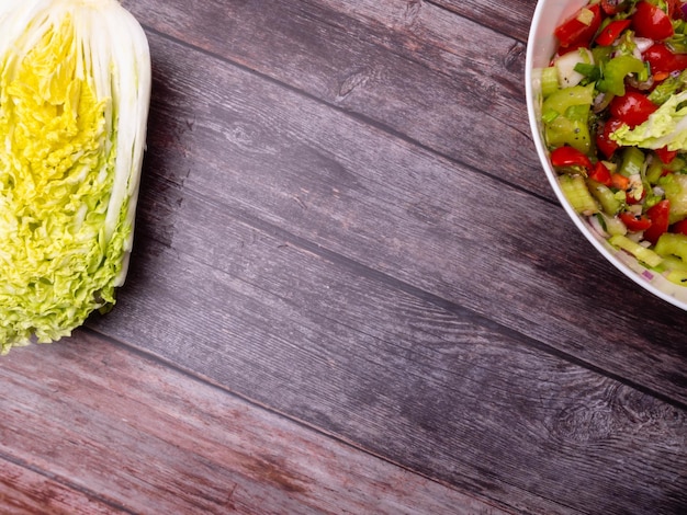 Salada de legumes fresca de repolho chinês tomate pimenta e cebola com azeite ou óleo de girassol na mesa de madeira Alimentos saudáveis