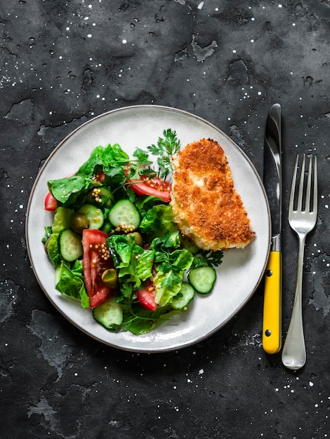 Salada de legumes fresca e halumi frito em migalhas de pão um delicioso almoço vegetariano em uma vista superior de fundo escuro