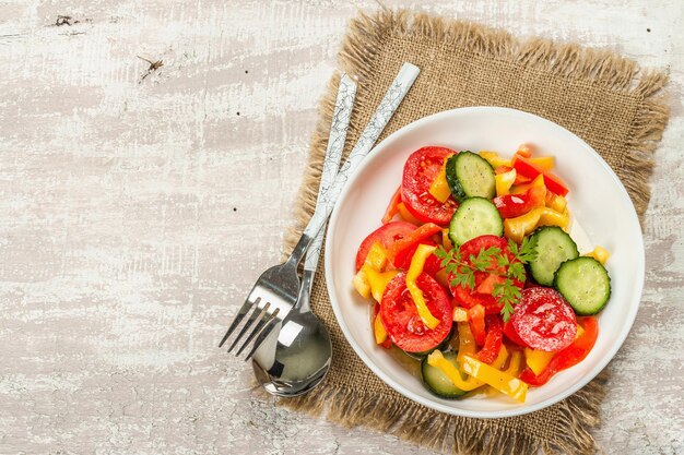 Salada de legumes fresca sazonal. Tomates maduros, pepinos, pimentões. Conceito de comida saudável. Fundo de madeira, vista superior