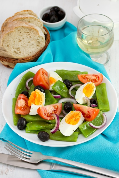 Salada de legumes no prato, pão e vinho branco