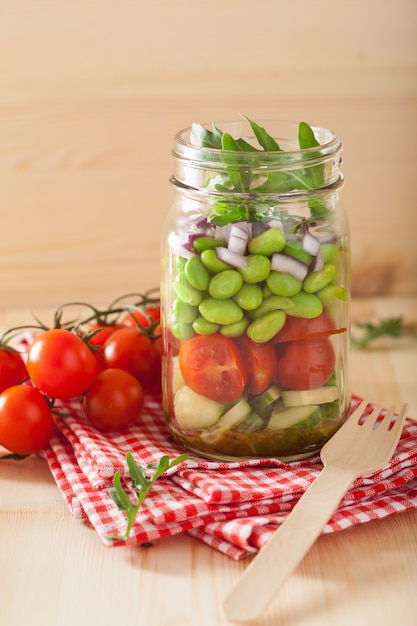 Salada de legumes saudável em frasco de vidro: tomate, pepino, soja, cebola