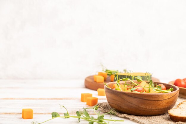 Salada de legumes vegetariana de brotos de ervilha microgreen de abóbora de tomate em fundo branco de madeira Espaço de cópia de vista lateral