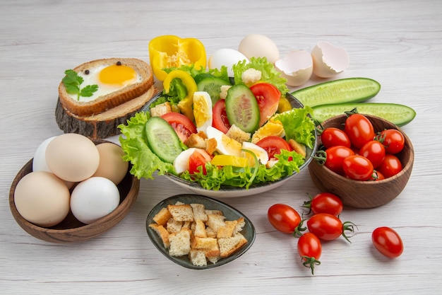 Salada de legumes vista frontal com ovos e temperos em fundo branco refeição madura comida café da manhã cor salada almoço