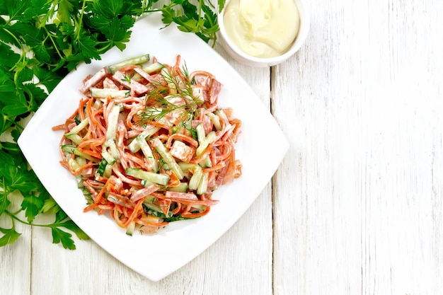 Salada de linguiça defumada cenoura picante tomate pepino e especiarias vestida com garfo de toalha de maionese e salsa em um fundo de tábua de madeira de cima