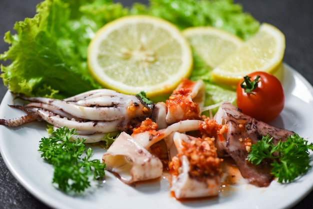 Salada de lulas com molho picante e ervas picantes e especiarias / Fatia de lulas grelhadas no prato no restaurante de frutos do mar