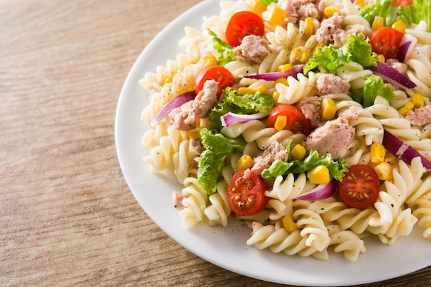 Salada de macarrão com legumes e atum na mesa de madeira.