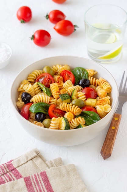 Salada de macarrão com tomate, abobrinha, azeitonas e espinafre. Alimentação saudável. Comida vegetariana.