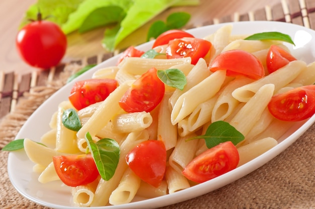 Salada de macarrão com tomate cereja e folhas de manjericão fresco