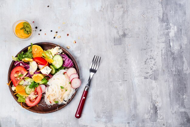 Salada de macarrão de fio de feijão com pepino e cenoura, salada vegetariana em um prato fundo de pedra