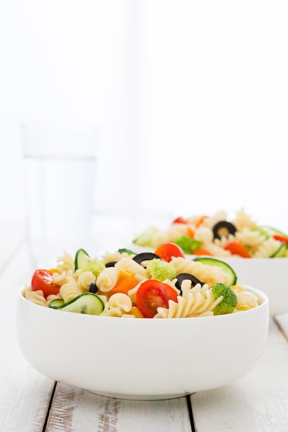 Salada de macarrão em uma tigela na mesa de madeira branca