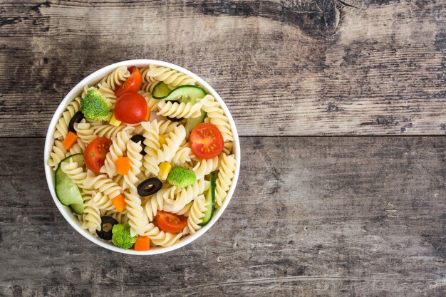 Salada de macarrão em uma tigela no espaço de cópia de vista superior de mesa de madeira