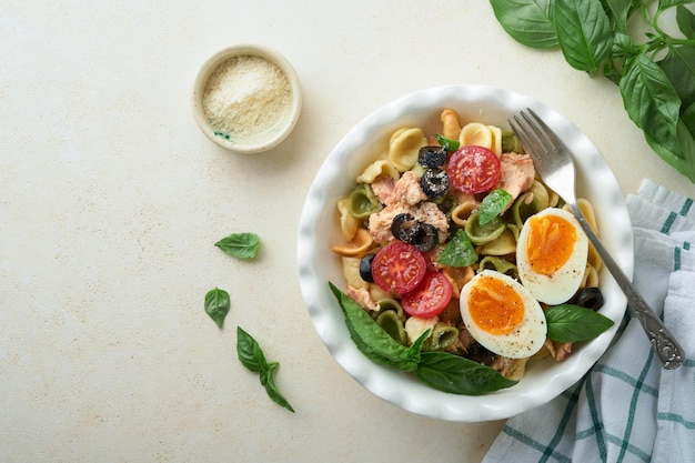 Salada de macarrão italiano Macarrão Orecchiette com atum tomate cereja azeitona manjericão e queijo parmesão no prato na pedra cinza ou fundo de concreto Cozinha tradicional italiana Flat lay Espaço para cópia