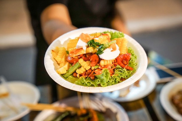 Salada de mamão Somtum Spicy com milho cozido em prato de papel no evento foodtruck street food Bangkok Tailândia