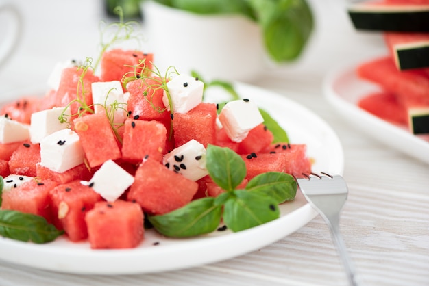 Salada de melancia com queijo feta e manjericão em prato branco