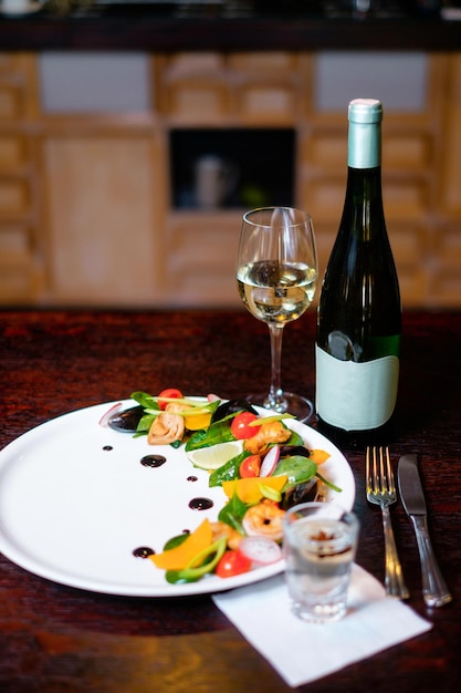 Salada de mexilhão em um prato branco com vidro e garrafa de vinho Conceito de um belo prato servindo para um restaurante