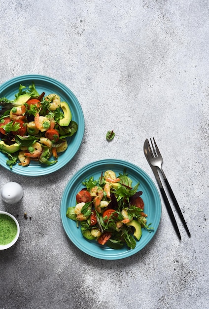 Salada de mistura verde com tomate e camarão e molho em um fundo de concreto vista de cima