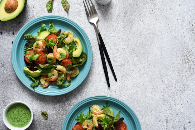 Salada de mistura verde com tomate e camarão e molho em um fundo de concreto vista de cima