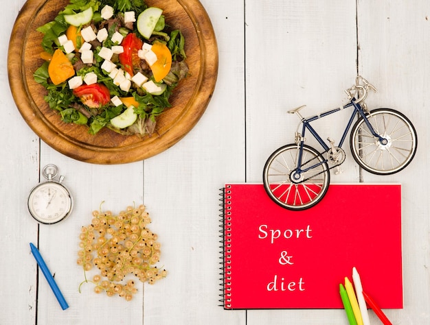 Salada de modelo de bicicleta de bloco de notas vermelho de legumes frescos com inscrição Sport dieta cronômetro