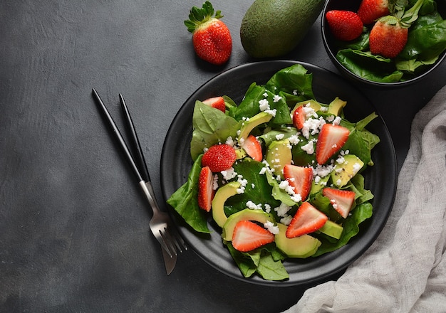 Salada de morango com espinafre, queijo feta, abacate, vinagre balsâmico e azeite em um prato