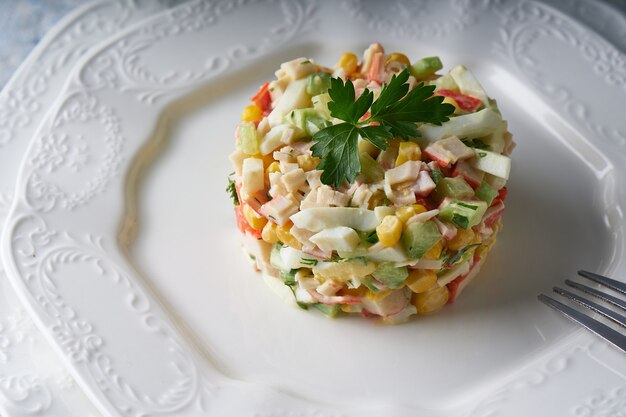 Foto salada de palito de caranguejo servida em prato branco na mesa de pedra cinza