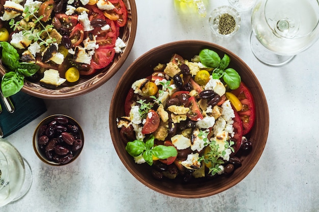 Salada de panzanella tradicional da Toscana italiana com tomate fresco e queijo em pratos de barro e vinho branco em uma garrafa e copos.