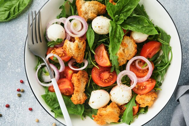 Salada de pão italiano Panzanella Comida tradicional da Itália com tomate mussarela bolas manjericão cebola e pão em fundo cinza claro Cozinha tradicional italiana Vista superior Espaço para texto