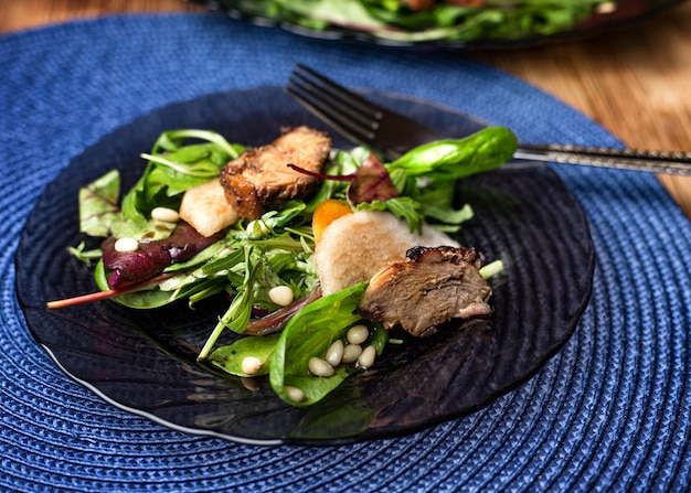 Salada de pato com pêra em mesa de madeira, temperada com pinhão