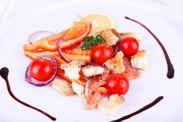Salada de peixe fresco com legumes no prato na mesa de madeira closeup