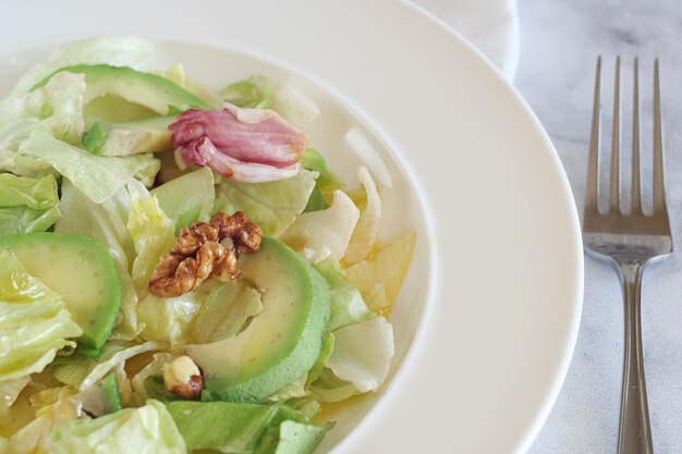 Salada de repolho, abacate e nozes em um prato sobre uma mesa de mármore. Café da manhã