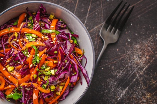 Salada de repolho em uma bacia cinzenta no fundo escuro. salada da couve vermelha e da cenoura.