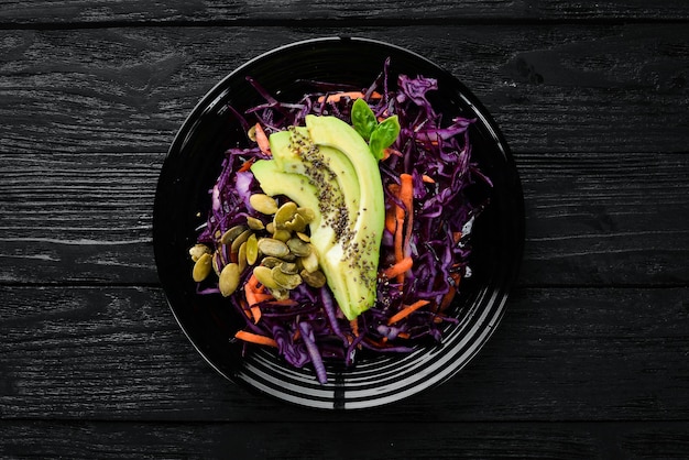 Salada de repolho roxo cenouras abacates e sementes de abóbora Vista superior Em um fundo preto Espaço para cópia grátis