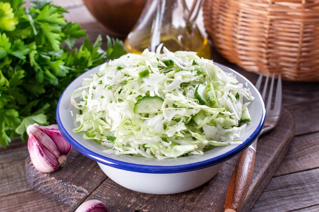 Salada de repolho saudável com pepino, cebola verde e salsa em um prato. Conceito de dieta alimentar