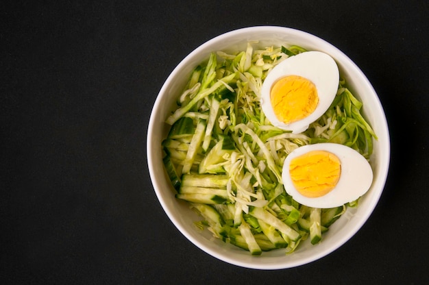 salada de repolho vegetariano com ovo cozido em uma vista superior de fundo preto