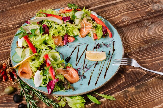 Salada de salmão com legumes e ervas em fundo de madeira