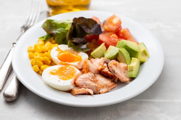 Salada de salmão com legumes e ovo cozido na chapa branca na cerâmica