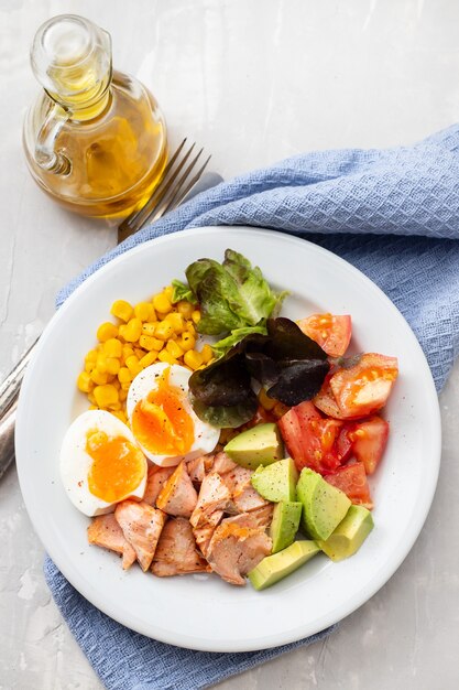 Salada de salmão com legumes e ovo cozido no prato branco na mesa de cerâmica