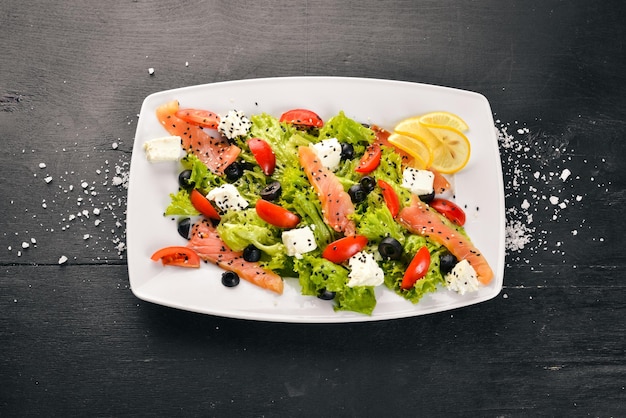 Salada de salmão salada de queijo feta folhas e legumes frescos no prato em um fundo de madeira vista superior espaço livre para texto