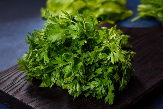 Salada de salsa e endro em uma tábua escura contra um fundo azul de concreto