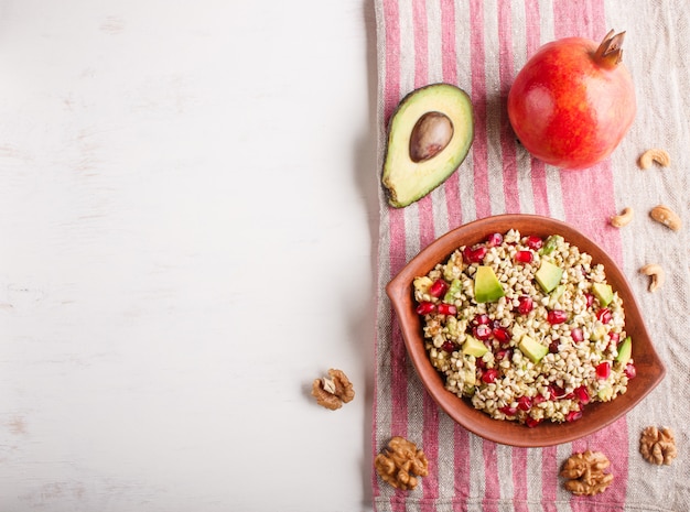 Salada de sementes germinadas de trigo, abacate, nozes e romã em placa de argila