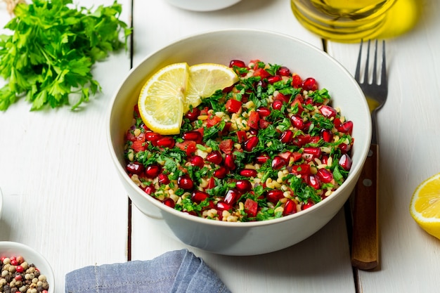 Salada de tabule com bulgur, hortelã, salsa, tomate e romã. Alimentação saudável. Comida vegetariana.