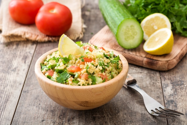 Salada de tabule com cuscuz em uma tigela de madeira na mesa rústica