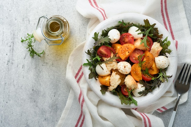 Salada de tomate cereja Panzanella toscana com mussarela de manjericão de rúcula e biscoitos de pão em tigela branca Salada italiana tradicional Comida saudável mediterrânea e