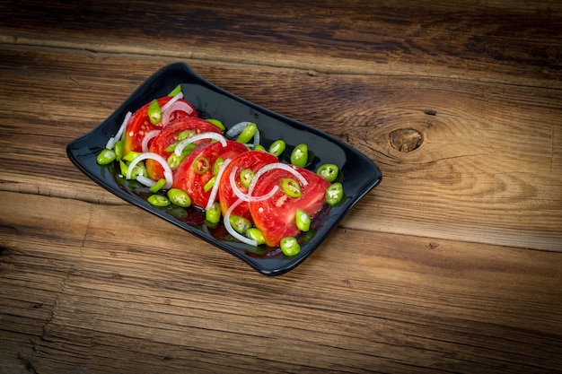 Salada de tomate e pimenta em fundo de madeira