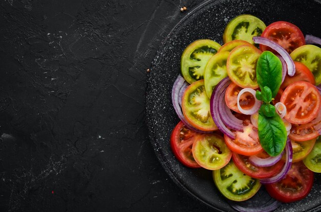 Salada de tomate fresco e cebola em um prato preto No fundo antigo Vista superior Espaço livre para o seu texto